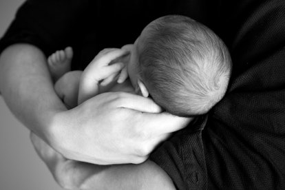 A person holding a newborn baby in black and white