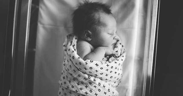 A newborn baby sleeping covered in a blanket. in a hospital
