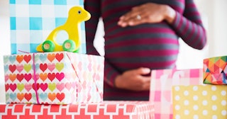 A pregnant mother standing next to a table full of packed gift boxes for a baby registry