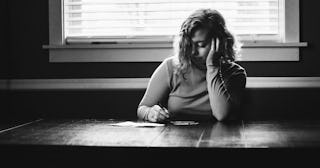 A young woman sitting at a table and writing notes on a paper