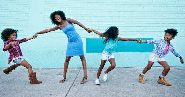 Mother with her three daughters posing, smiling and holding hands