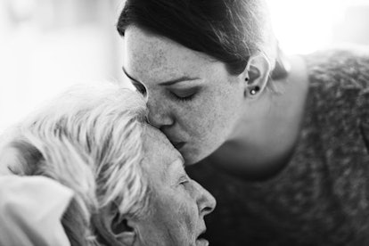 A woman kissing her older mother in the forehead. 