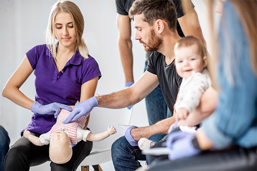 A man teaching a woman how to preform CPR on a baby in a CPR class.