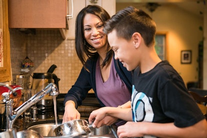 A kid helping his mom clean the dishes in the kitchen.