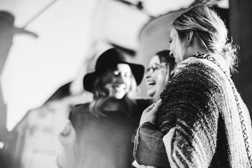 Three female friends standing together hugging and laughing