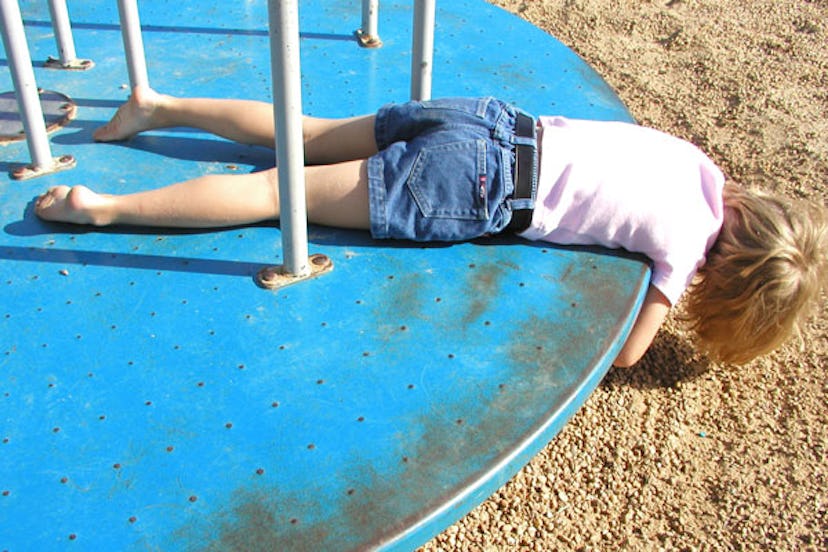 An impulsive ADHD kid lying down on a spinning playground diameter 