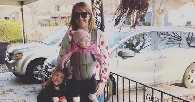 A mother with her two kids in the front yard with cars parked behind them