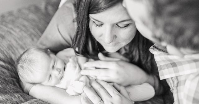 Parents holding their newborn baby while the woman thinks being a mom isn't a job