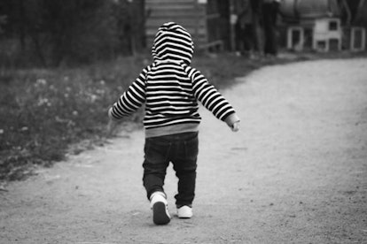A little boy in a black and white hoodie wandering off 