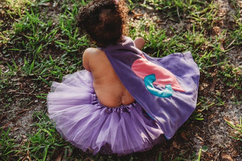 Baby in ballet skirt and a cloak in purple.