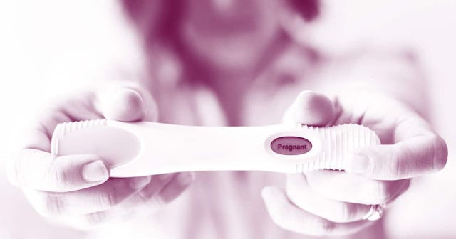 Woman holding the pregnancy test that says "Pregnant"