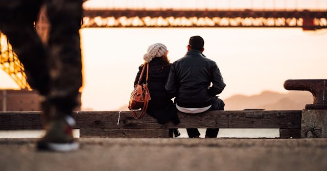 Parents on a date sitting on a bench.