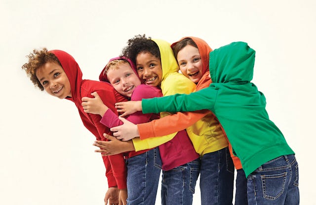 A group of kids wearing gender-neutral clothes, hoodies in different colors paired with blue jeans f...