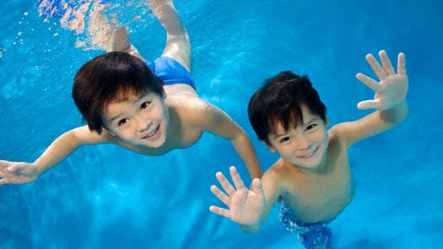 Two boys swimming in the pool and having fun.