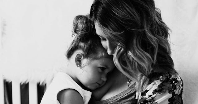 A widowed single mom holding her daughter who is leaning on her chest 