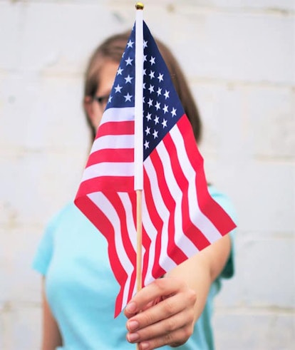 A woman holding little American flag covering her face