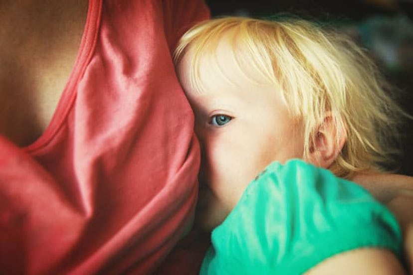 A blonde toddler being breastfed 