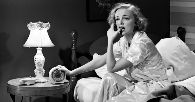 The woman anxiously sitting on the bed in the middle of the night, having trouble sleep