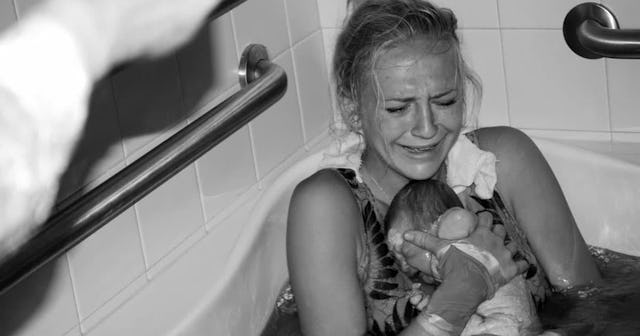 Woman holding her newborn baby after giving birth in water