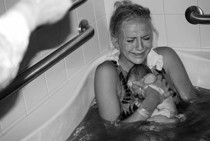 Woman holding her newborn baby after giving birth in water 