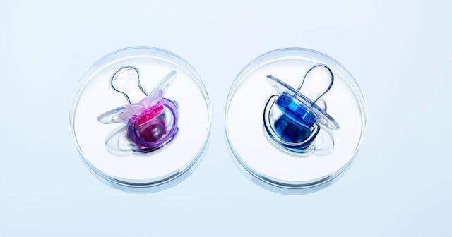 Two pacifiers, a blue and a pink one laid out on a blue background