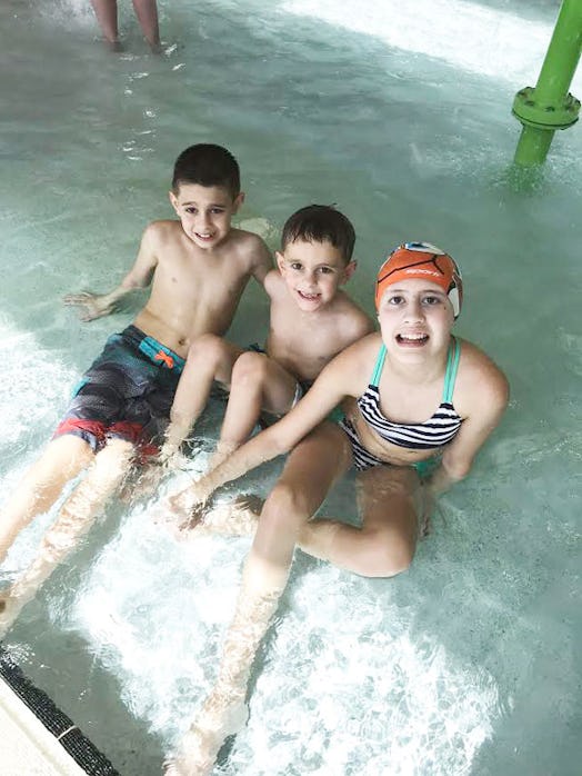 Cara's two sons and her daughter who got sick sitting in a swimming pool and smiling