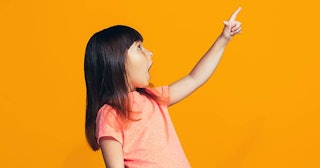 A small girl points out a differently-abled person with a yellow background