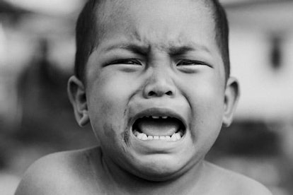 A short-haired boy crying in a black and white photo 