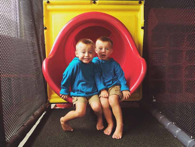 Twin brothers in matching outfits sitting on a slide 