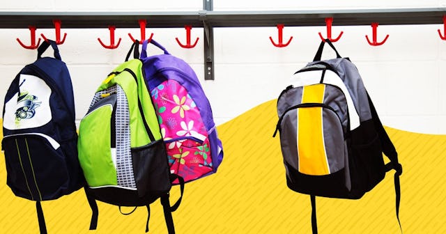Four children's backpacks filled with school supplies hanging on the gallows on a blue and yellow ba...
