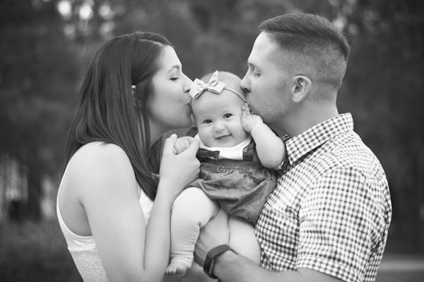 A man and a woman kissing their daughter who is wearing a hair bow