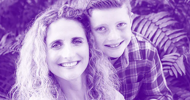 A young boy hugging his mom, both smiling.
