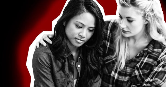 A blonde woman hugging and comforting a brunette woman in black and white with a black and red backg...