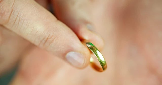 A woman holding a golden wedding ring 