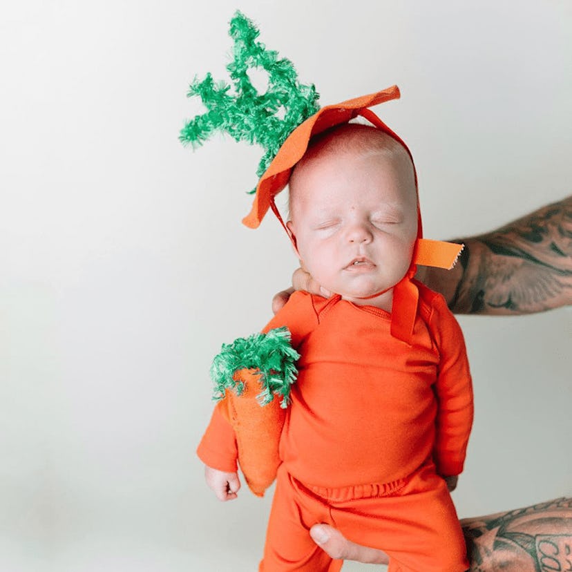 A baby in an orange carrot costume 