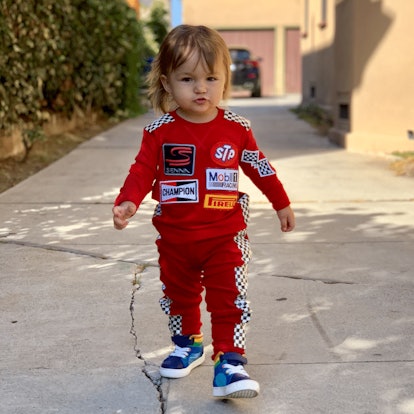 A toddler walking in a red race car driver kids costume