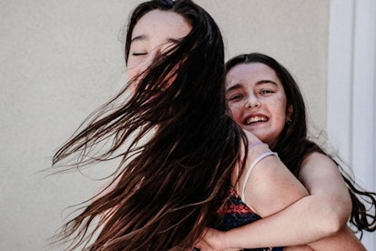 A mother and her stepdaughter hugging each other while smiling and dancing