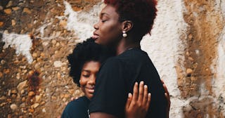 A mom hugging her stepdaughter while they're both smiling