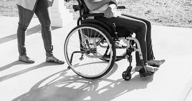 A mother pushing her preteen daughter in a wheelchair in black and white
