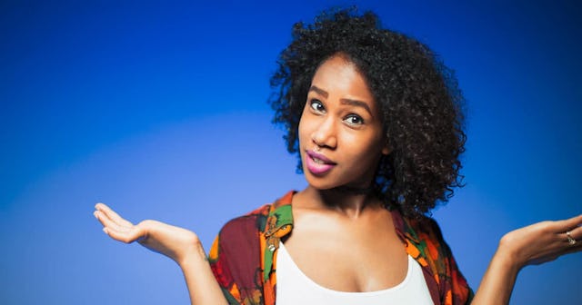 A woman with short curly hair in a white top with her hands suggesting she doesn't need to explain h...