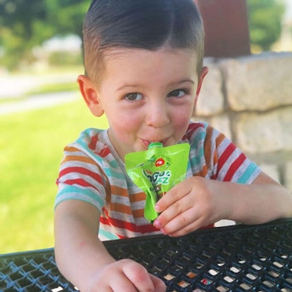 Stephanie Hanharan's son smiling in a striped shirt while drinking juice