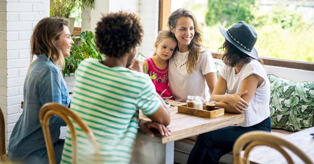 A mom squad with four moms and one holding her child in her lap at a restaurant