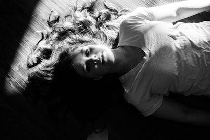 A girl lying on a floor in a black and white picture looking worried after being bullied