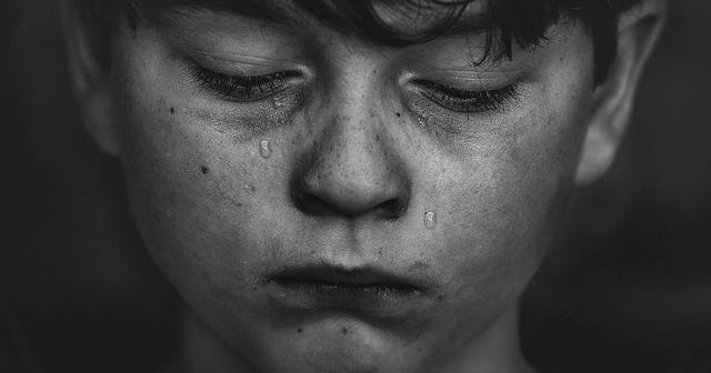 A portrait of a boy crying because he is being bullies in black and white