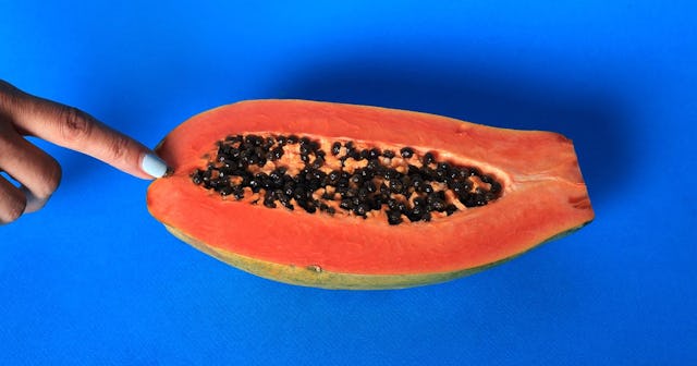 A Hand Touching Half A Papaya