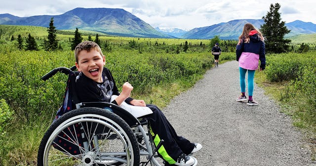 Allyson Buck's son in a wheelchair laughing while on an outdoors hike