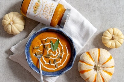 New at Trader Joe's; a bowl of orange soup beside three white pumpkins and the soup jar