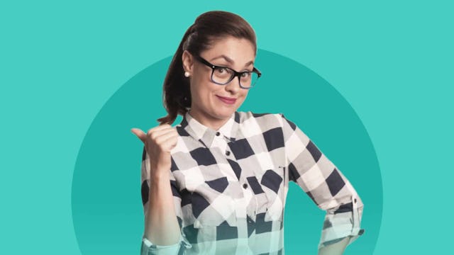 A woman with a ponytail, glasses, and a plaid button-up shirt pointing behind her while looking sugg...