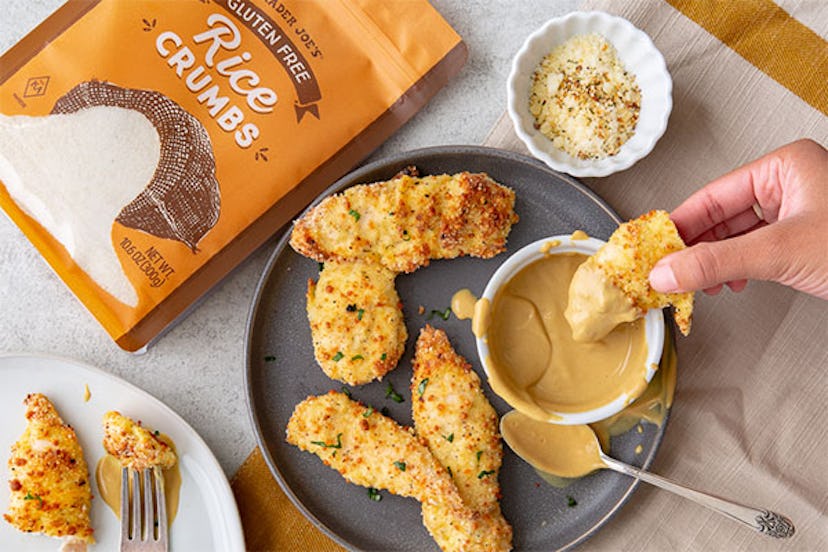 New at Trader Joe's; hand dipping chicken tender into sauce, other chicken tenders on plate