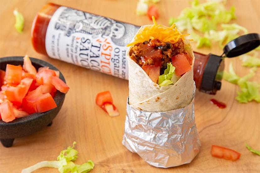 New at Trader Joe's; taco standing beside bowl of peppers with taco sauce bottle in background